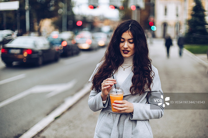 年轻女人在户外享用橙汁图片素材