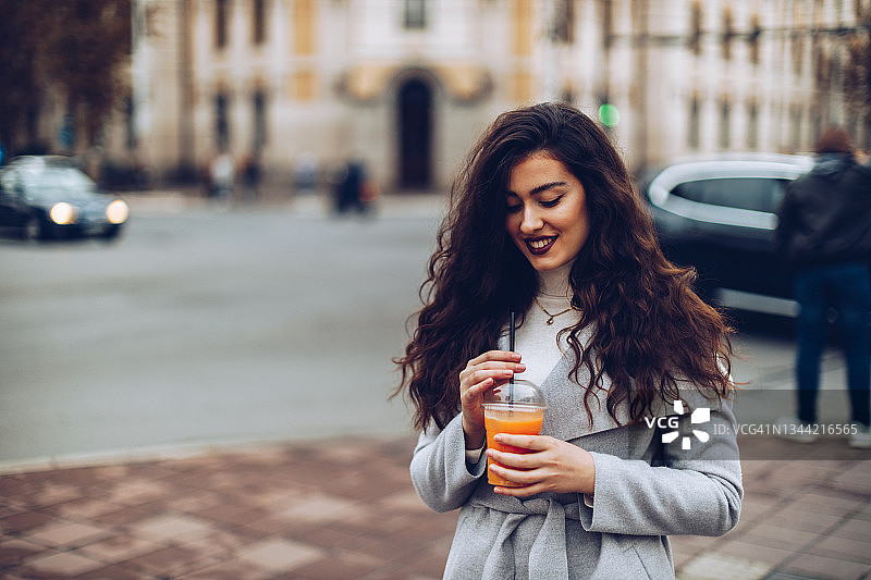 年轻女人在户外享用橙汁图片素材