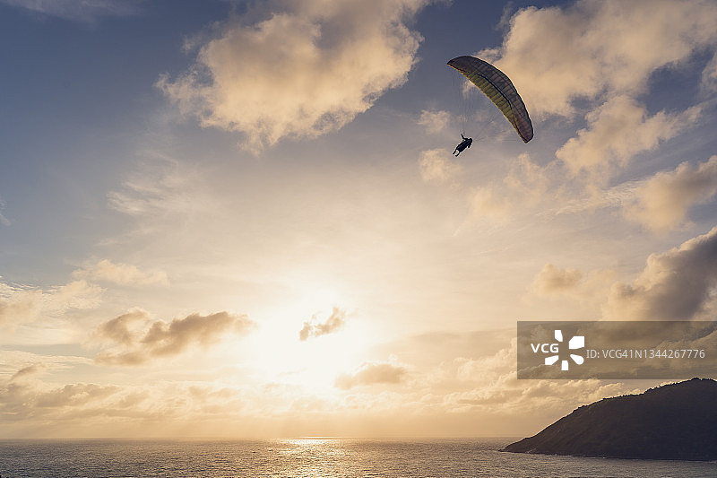 男人在海上滑翔，俯瞰山脉和日落图片素材