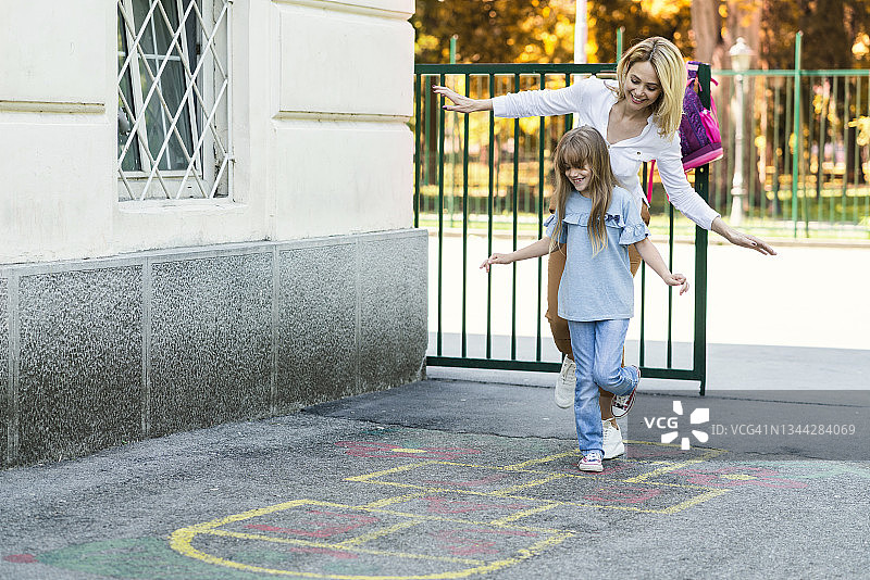 快乐的女学生和妈妈在学校操场上玩跳房子图片素材