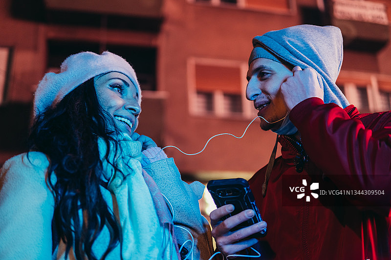 快乐情侣在街头分享在线音乐图片素材