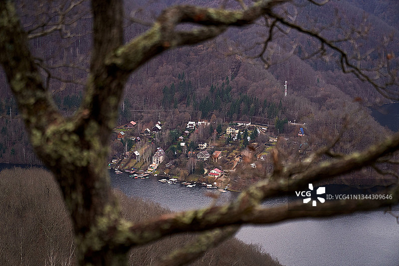 树枝间的景色：山间湖岸边的村庄图片素材
