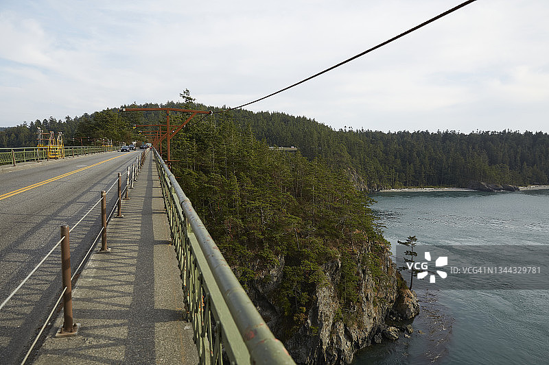 在华盛顿州普吉特海湾的迪ception Pass Bridge上行驶的汽车（在建）图片素材