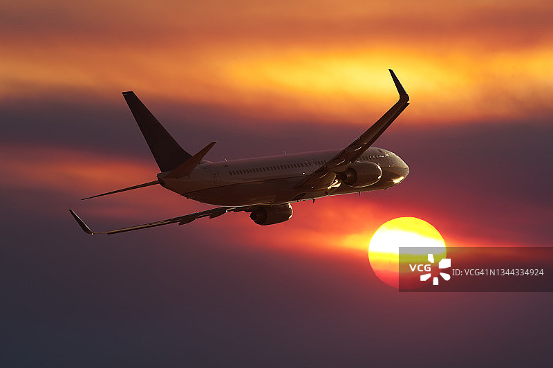 一架波音737客机在日落时分飞行图片素材