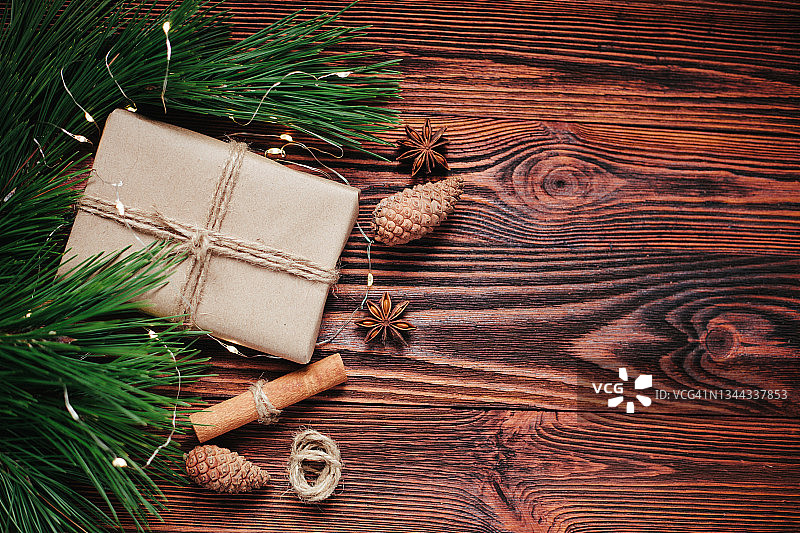 纸工艺礼品盒圣诞贺卡：天然松树绿枝和松果冬季装饰，深棕色木背景图片素材