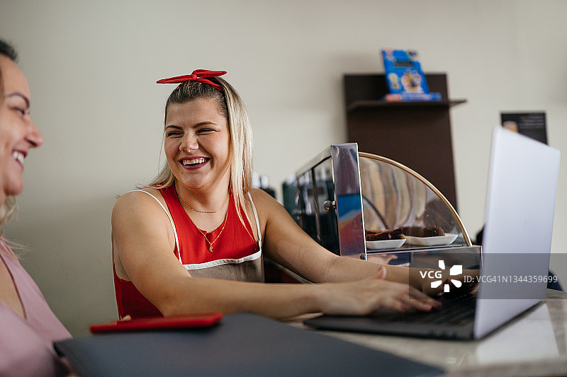 微笑餐馆老板使用笔记本电脑图片素材