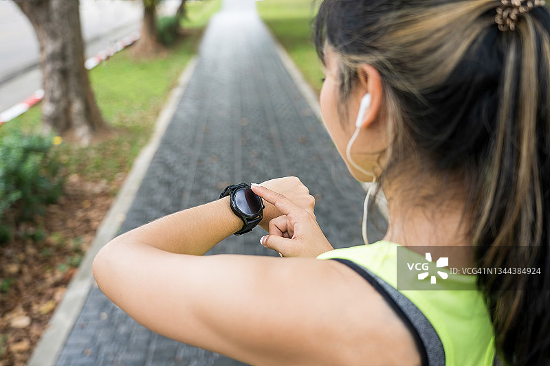 年轻的慢跑者准备跑步，正在看运动智能手表，检查性能或心率脉搏轨迹，在城市户外运动和健身图片素材