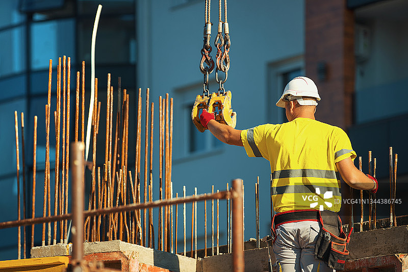 建筑工人将货物装载到建筑起重机上图片素材