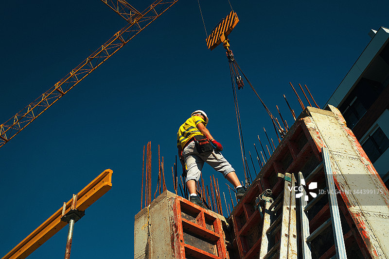建筑工人将货物装载到建筑起重机上图片素材