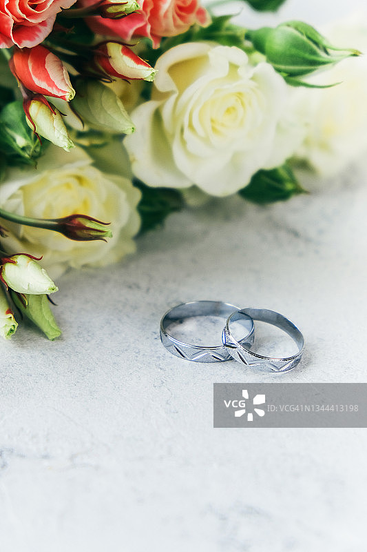 白色纹理表面上的银色结婚戒指和玫瑰图片素材