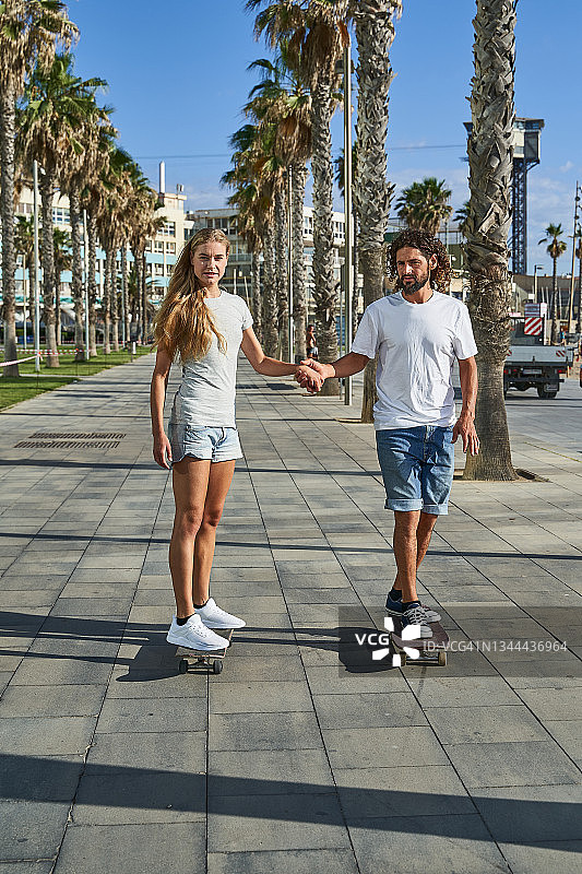 情侣手牵手滑滑板，直视前方图片素材