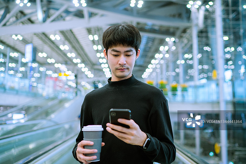 商人在机场扶梯上使用手机图片素材
