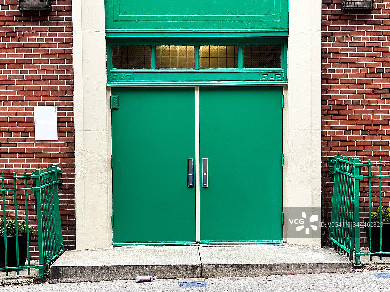 城市公立学校建筑的侧门已关闭，人行道上有社交距离标志，旁边有一个废弃的塑料瓶图片素材