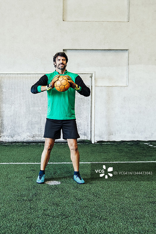 足球守门员抱球靠在门柱上图片素材