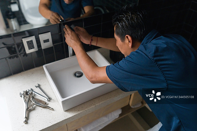 水管工修理浴室水槽中的水龙头图片素材