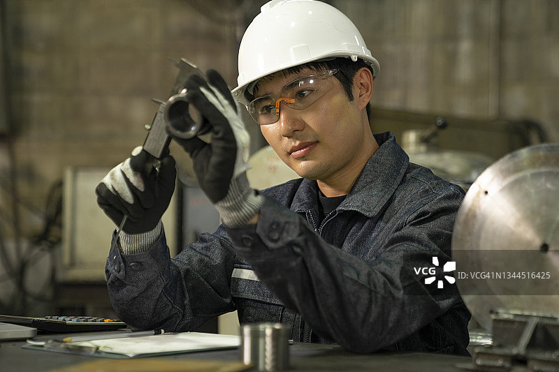 金属加工厂工人检查钢制圆筒尺寸图片素材