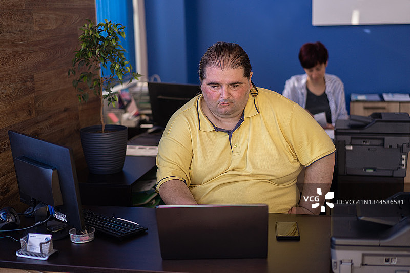 坐在办公桌前工作的肥胖男子图片素材