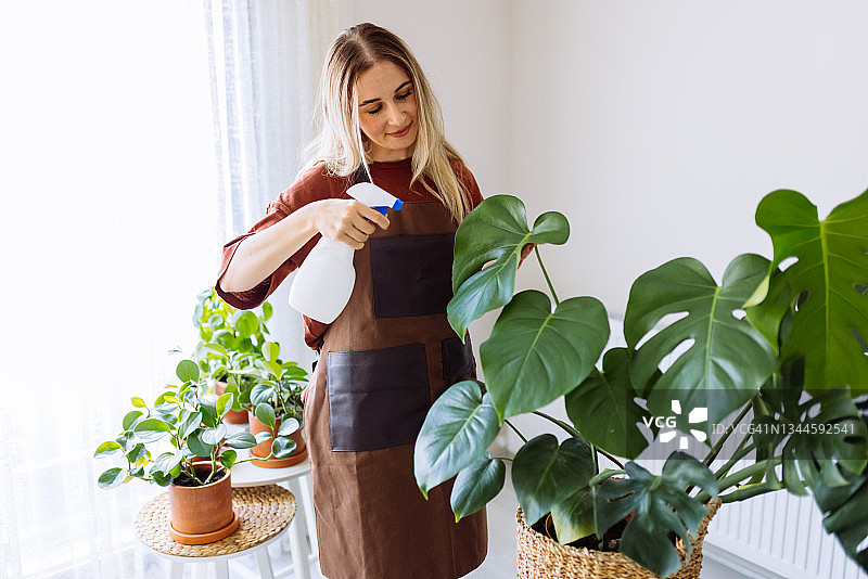 可爱的家庭主妇带着花盆里的花和园艺用具图片素材