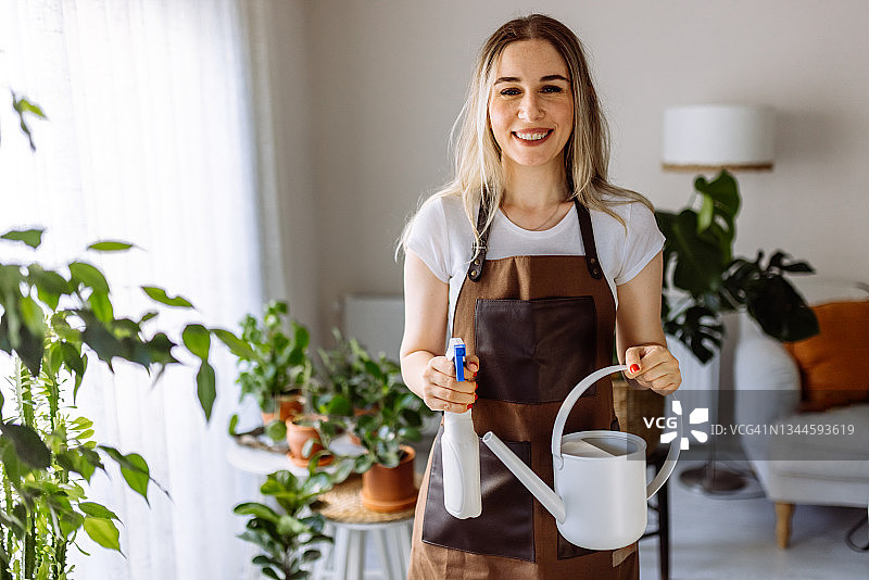 可爱的家庭主妇带着花盆里的花和园艺用具图片素材
