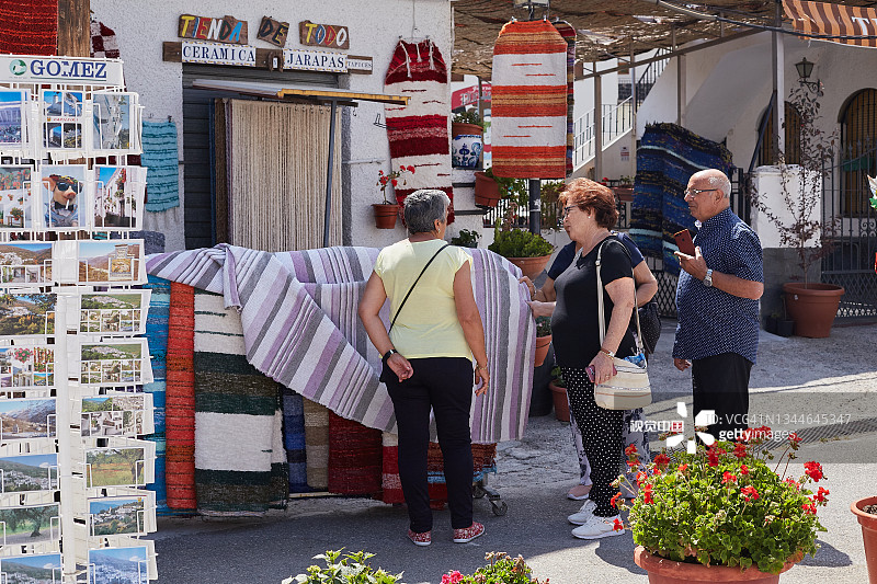游客挑选传统手工纪念品、地毯、明信片和当地的塞拉诺火腿图片素材