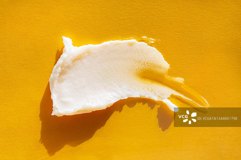米黄色润肤霜在黄色背景上的涂抹，天然护肤化妆品概念图片素材