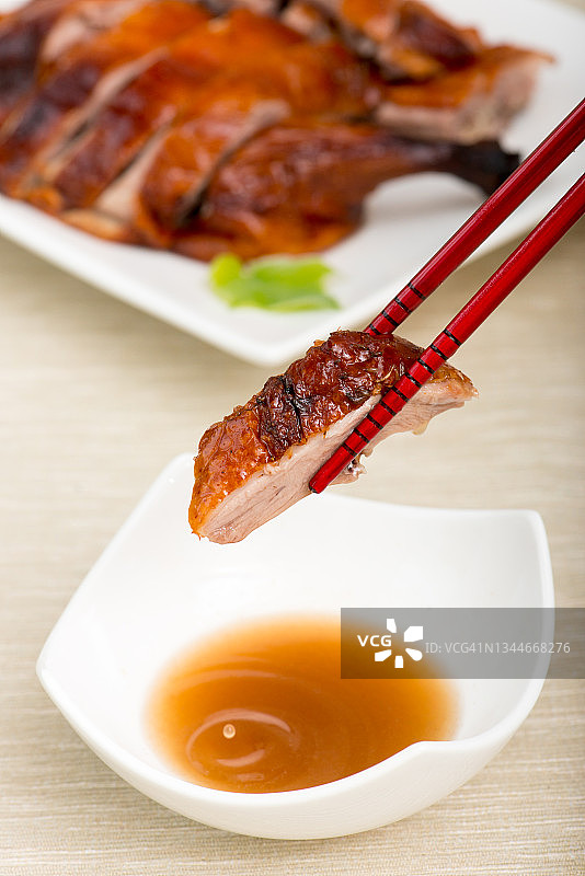 香酥烤鸭：将烤鸭肉蘸上李子酱图片素材