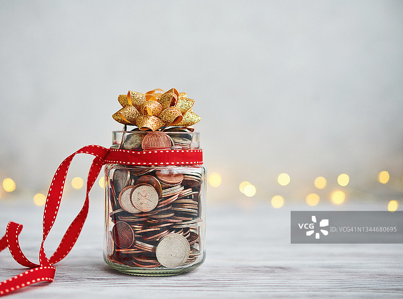 装满硬币和圣诞丝带蝴蝶结的节日储蓄罐图片素材