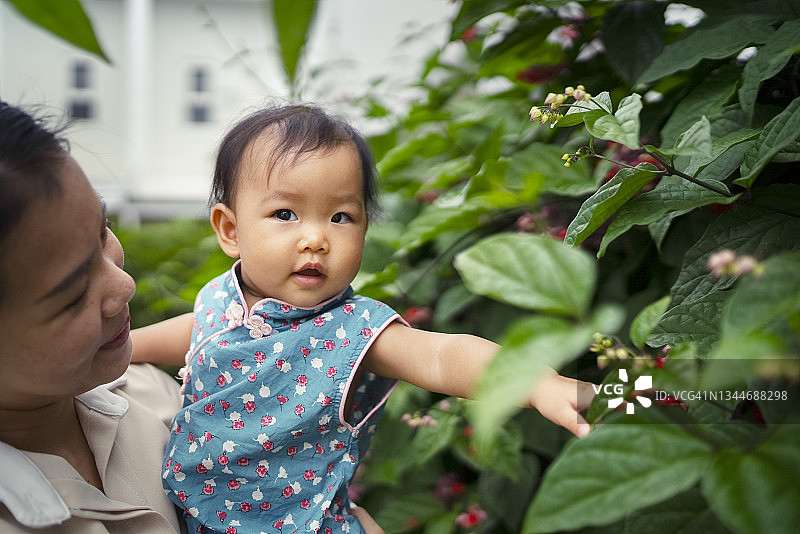 亚洲年轻成人母亲和女儿在家里后院附近的户外一起玩耍图片素材