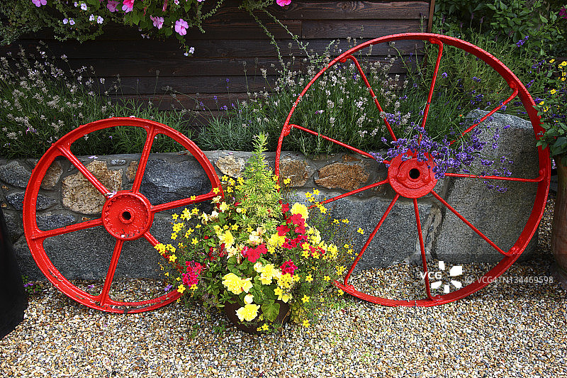 花卉装饰和旧马车轮，位于欧洲海峡群岛格恩西岛圣彼得港的一所房子里图片素材