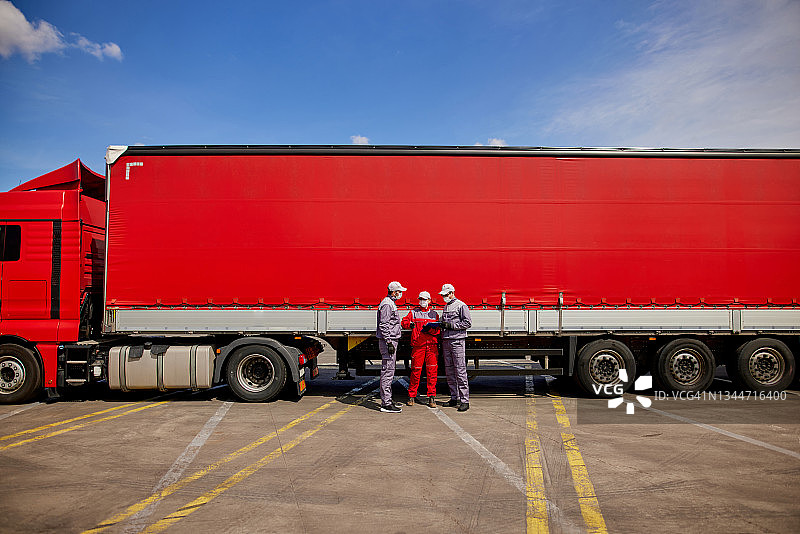 疫情期间查看发货清单的三个送货员图片素材