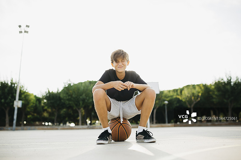 男孩坐在篮球上图片素材