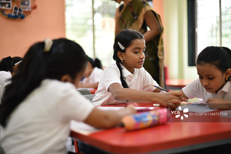 女学生帮助同学完成作业图片素材