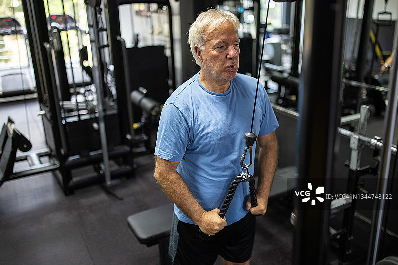 年长的男人在健身房使用下拉式器械锻炼图片素材
