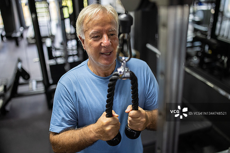 年长的男人在健身房使用下拉式器械锻炼图片素材