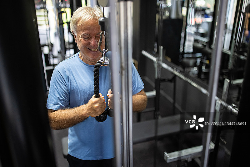 年长的男人在健身房使用下拉式器械锻炼图片素材
