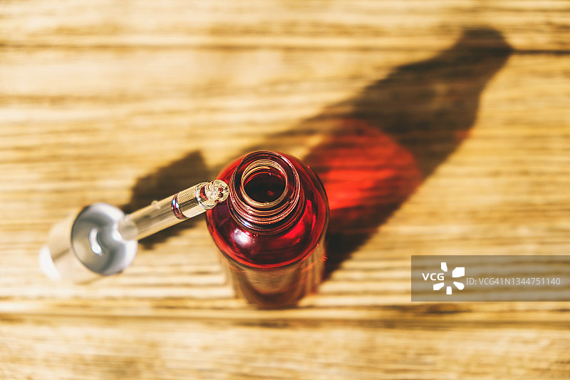 木质表面上的红色玻璃滴管瓶图片素材