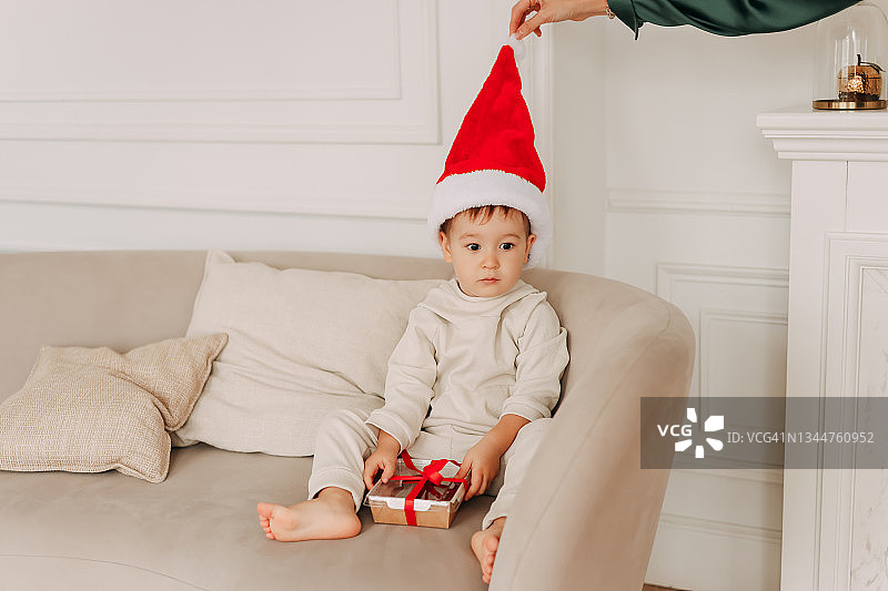 圣诞节概念：戴圣诞帽的小男孩打开礼物盒图片素材