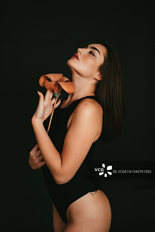 年轻女人拿着百合花，身穿连体泳衣图片素材