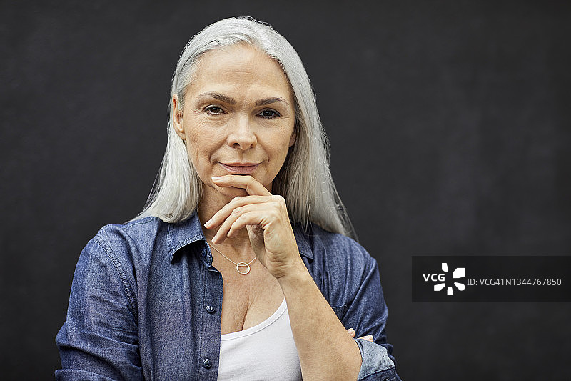 自信的中年妇女靠墙站立图片素材