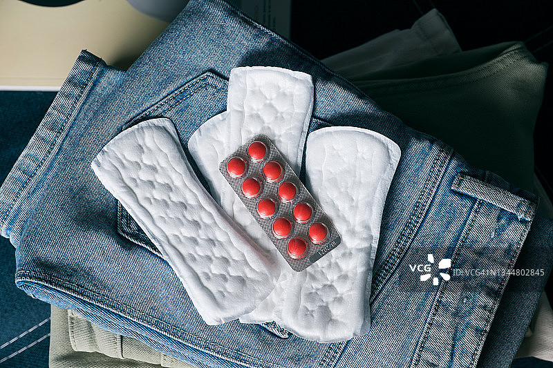 月经期用卫生巾和卫生护垫（女性用品、药丸、药品在牛仔裤上），旅行打包携带个人物品，经期、月经概念，妇科保健图片素材