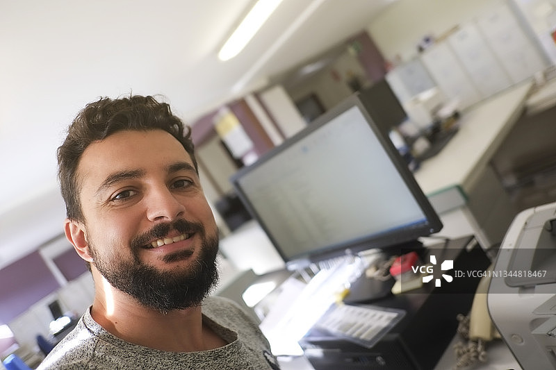 在办公室微笑看着镜头的络腮胡男人图片素材