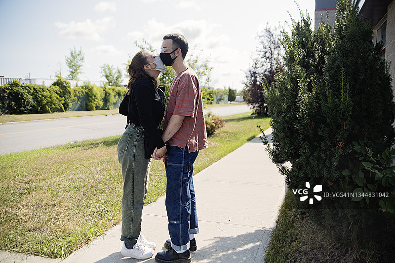 千禧一代情侣戴着口罩在街上亲吻图片素材