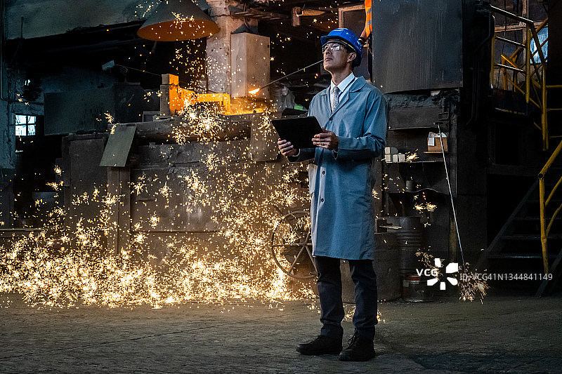身穿工作服的经理在铸造厂，背景中有热火花图片素材