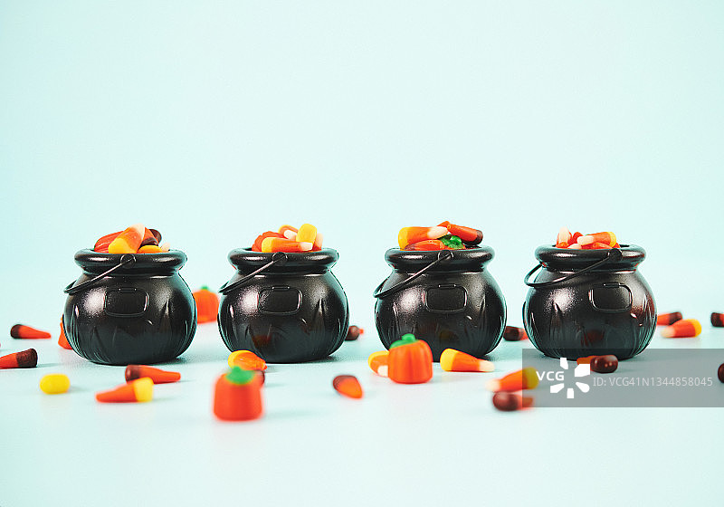 万圣节背景，四个女巫大锅装满不给糖就捣蛋的糖果图片素材