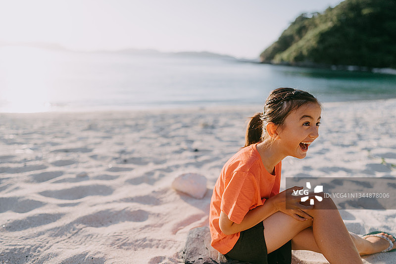 日落时分在海滩上欢笑的可爱女孩图片素材