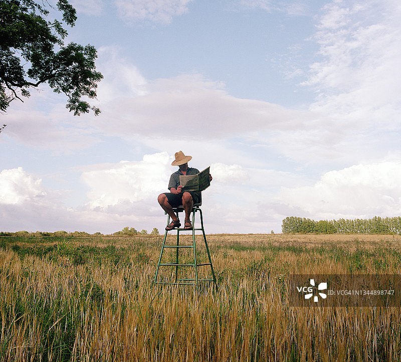 农民在田野里看报纸图片素材