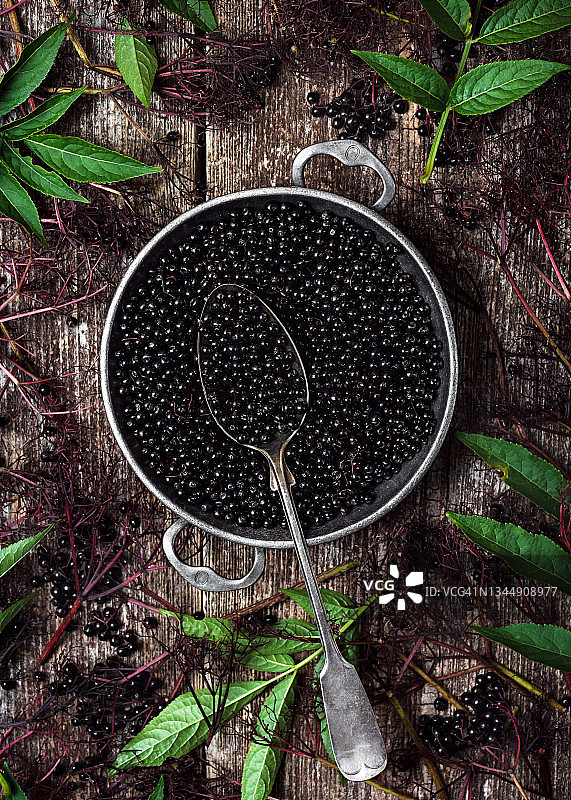 深色乡村木质背景上的金属复古锅中的有机黑接骨木浆果图片素材