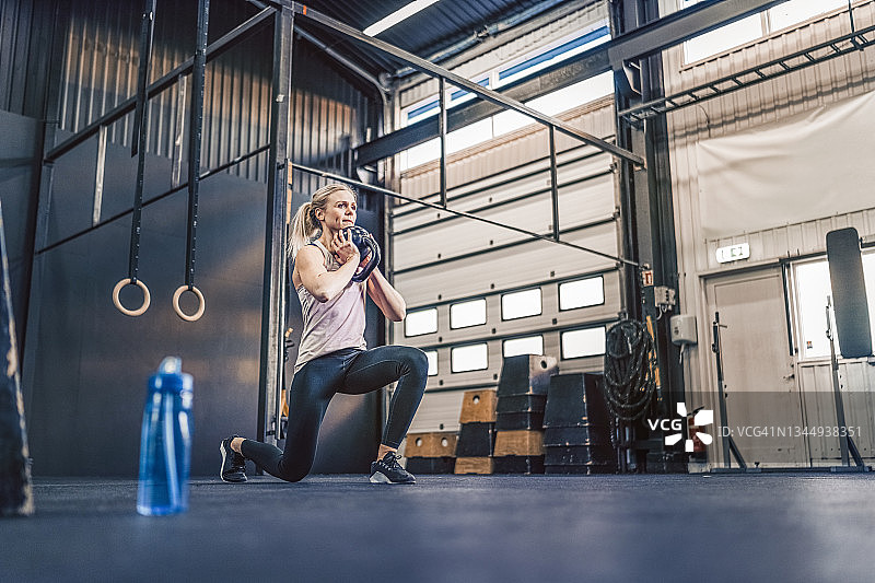 在健身房用壶铃锻炼的女运动员图片素材