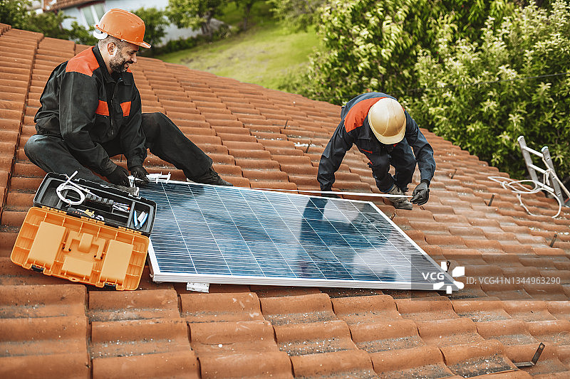 两名工人准备在屋顶安装太阳能电池板图片素材