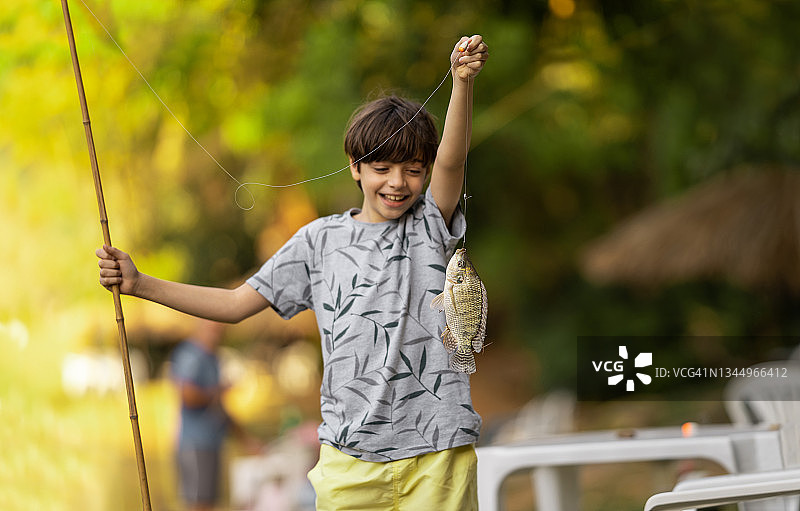 快乐的男孩在湖里钓鱼图片素材